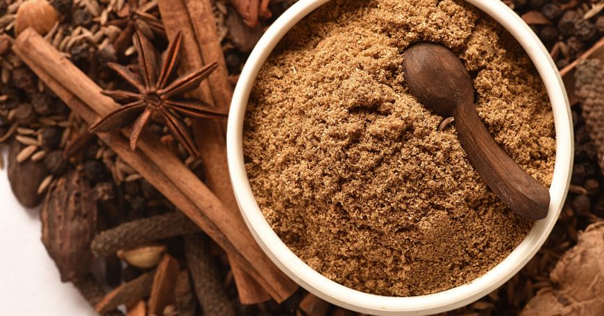 garam masala en un cuenco rodeado de especias sueltas